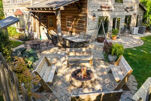A stone building with a patio area featuring a fire pit, outdoor seating, and potted plants. - Peninsula Lodge Fish Creek (Gibraltar)