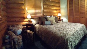 A cozy log cabin bedroom with a large bed, two nightstands, a chair, and a wardrobe. - Peaceful, Mountain Setting.  Yellowstone Country. (Livingston)