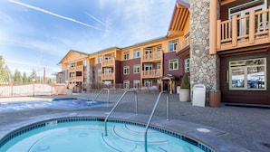 A hotel with a swimming pool, stone pillars, and wooden balconies. - Sunstone #329 Ski In Ski Out! 2 Bedroom 2 Bath (Mammoth Lakes)