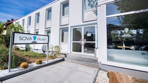 A modern SOVA Hotel building with a signboard, large windows, and a clean entrance. - SOVA Hotel (Kassel)