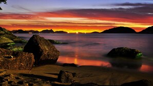 A coastal landscape with large rocks, calm water, and a sunset. - Tupiniquim Hostel Rio de Janeiro (Rio de Janeiro)