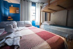 A room with a bunk bed, a bed with a red and beige quilt, a lamp, and a window with curtains. - Tupiniquim Hostel Rio de Janeiro (Rio de Janeiro)
