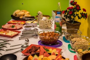 A table with various food items and utensils, including bread, fruits, and a bowl of nuts. - Tupiniquim Hostel Rio de Janeiro (Rio de Janeiro)