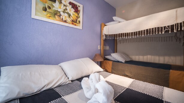 A hotel room with a bed, pillows, a blanket, a lamp, and a painting on the wall. - Tupiniquim Hostel Rio de Janeiro (Rio de Janeiro)