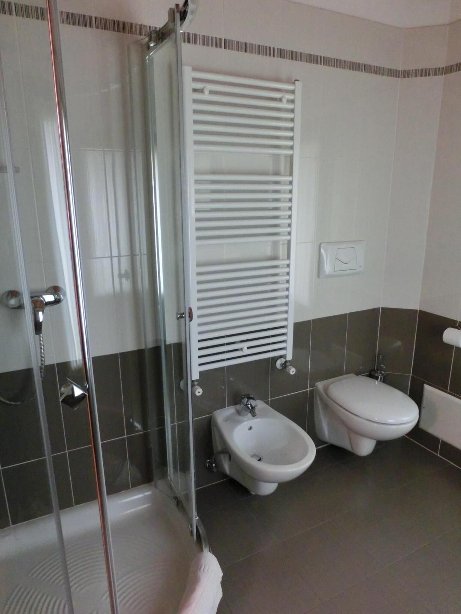 A bathroom with a glass shower enclosure, a bidet, and a toilet.