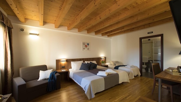 A hotel room with two beds, a sofa, a desk, and a wooden ceiling.