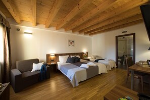 A hotel room with two beds, a sofa, a desk, and a wooden ceiling. - Hotel C25 (Ponzano Veneto)