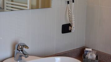 A bathroom with a white sink, a mirror, a towel rack, and a hairdryer mounted on the wall.