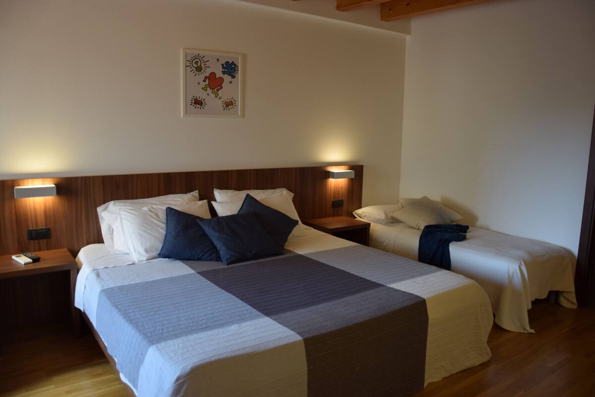 A hotel room with two beds, a wooden headboard, bedside lamps, and a wall-mounted artwork.