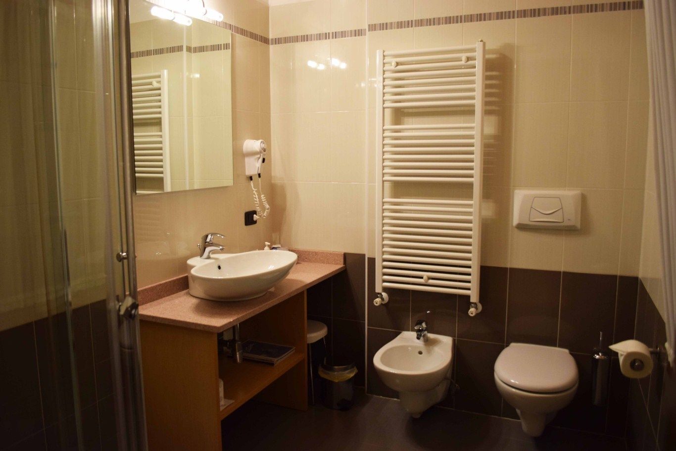 A bathroom with a sink, bidet, toilet, and a towel rack.