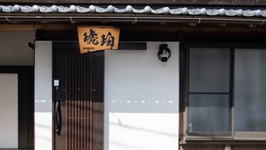 Un bâtiment doté d’une entrée de style japonais traditionnel, d’une porte en bois et d’une enseigne avec des caractères japonais.