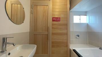 A modern bathroom with two sinks, a large mirror, and a wooden door with a sign.
