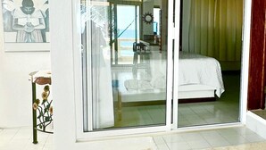 Una habitació amb un llit, una porta corredissa de vidre que dona a un balcó i un quadre a la paret.