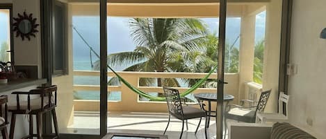 A balcony with a view of the sea, a hammock, and a table with chairs.