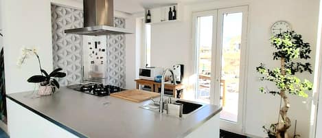 A modern kitchen with a central island, built-in appliances, and a large window.