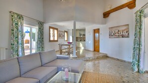 A spacious living area with a sofa, a glass coffee table, and a kitchen in the background. - Luxurious Villa with air conditioning and pool Marquesa GU 4 People (Denia)