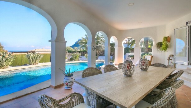 A poolside dining area with a view of the ocean and mountains. - Luxurious Villa with air conditioning and pool Marquesa GU 4 People (Denia)