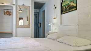 Une chambre à coucher comprenant un lit, une table de chevet, un miroir et une porte donnant sur une salle de bain.
