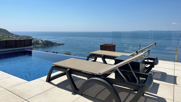Une piscine à débordement avec des chaises longues et une vue imprenable sur l’océan.