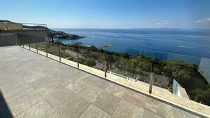 Une terrasse offrant une vue sur la mer et sur une côte lointaine.
