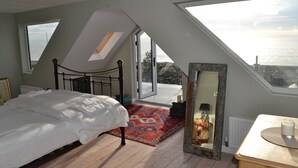 Een slaapkamer met dakraam, een bed, een tapijt met rood patroon, een dressoir en een spiegel.