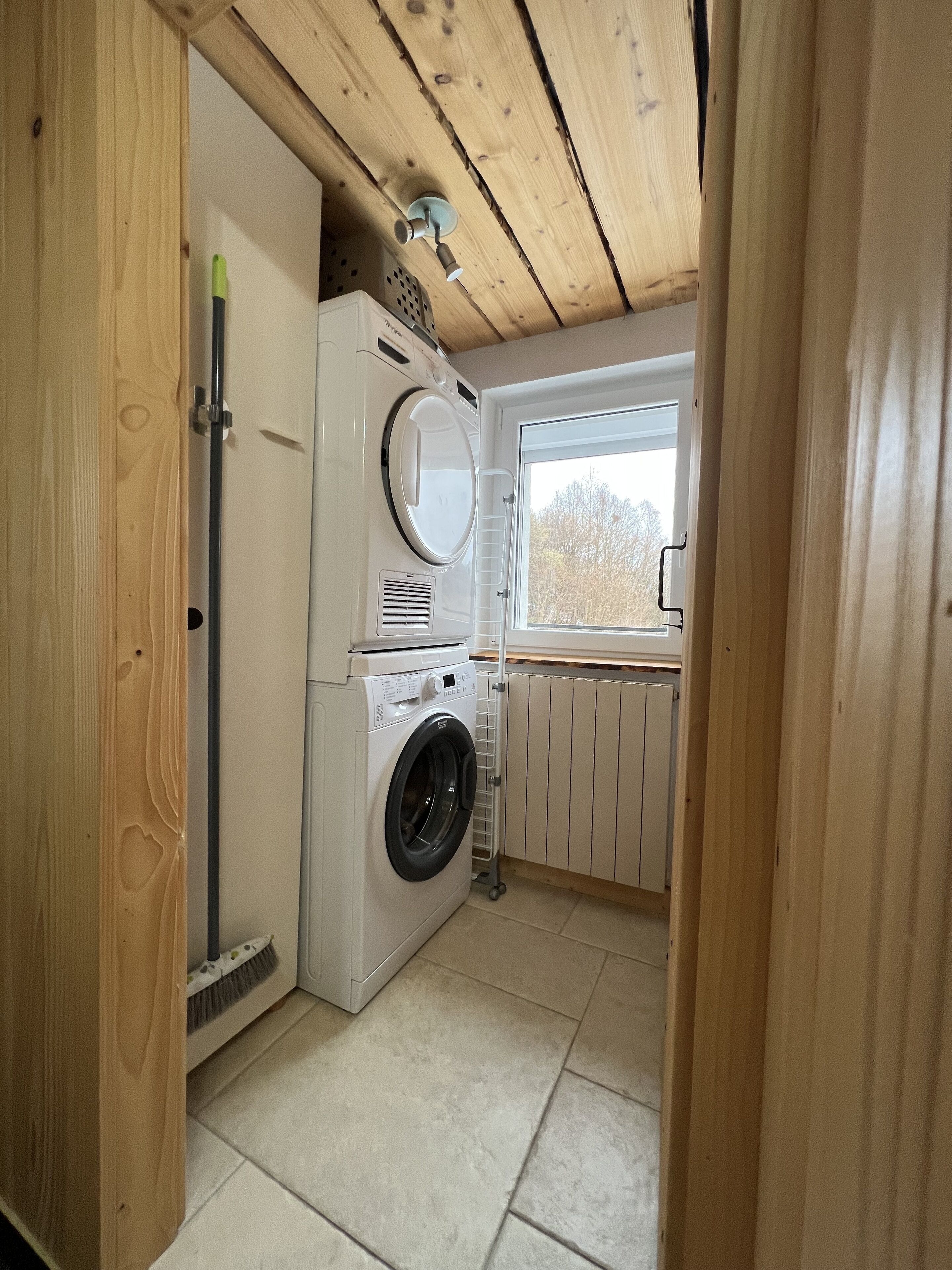 A laundry room with a washing machine, dryer, and a window with a view of trees.