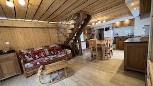 Un interior acogedor de madera con un sofá, una mesa de comedor y un trineo.