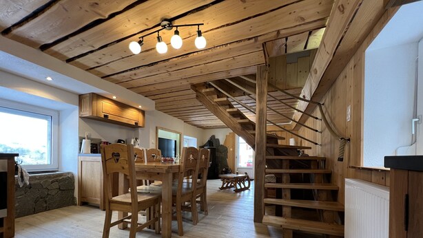 Un interior de madera con comedor, cocina y escalera.