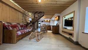 Un interior de madera con un sofá, una mesa de comedor y una zona de cocina.