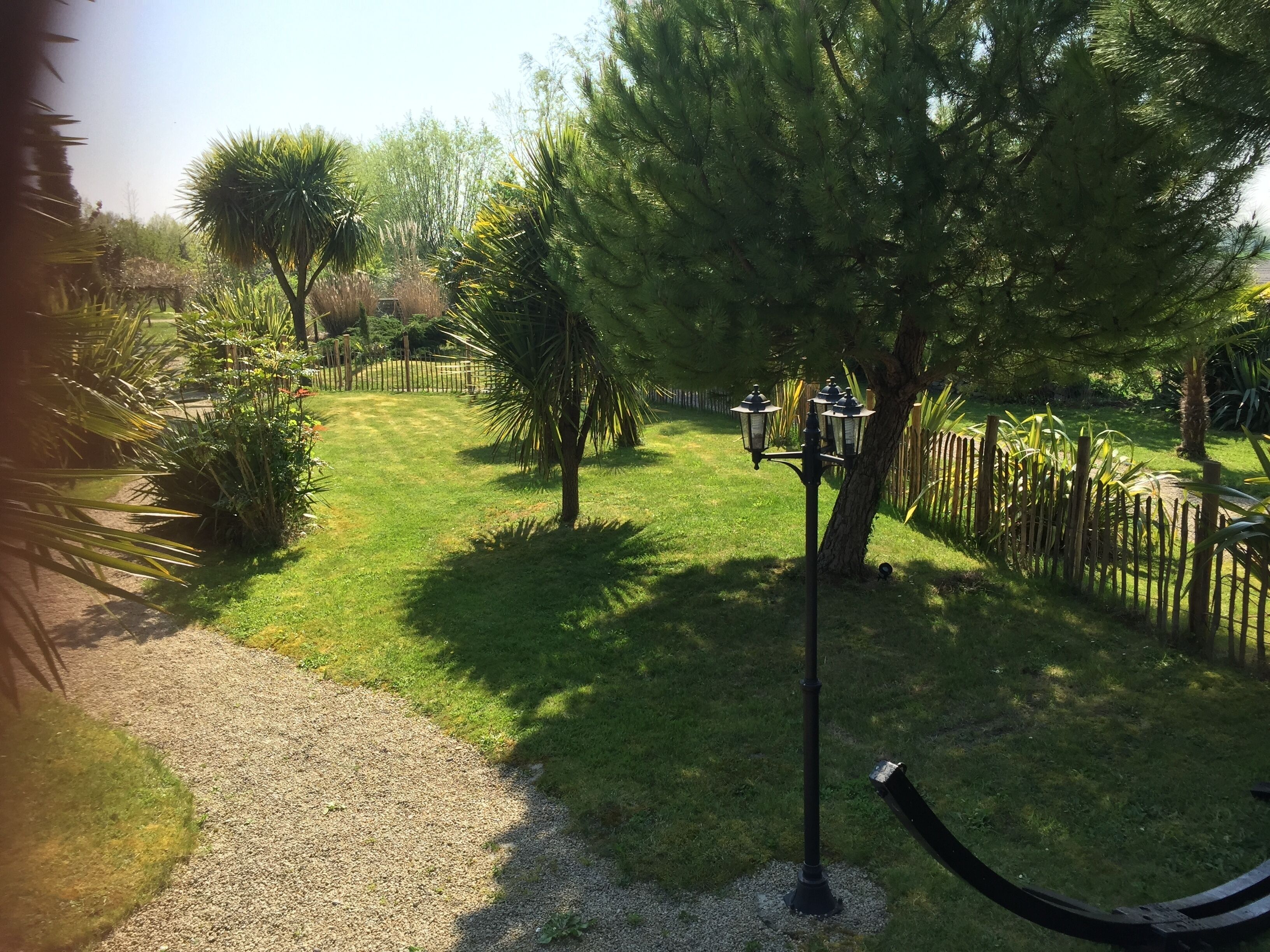 Un jardin avec un chemin de gravier, une clôture en bois et un lampadaire.