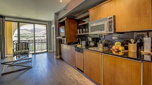 Una cocina moderna con armarios de madera, microondas y vistas a montañas a través de amplios ventanales correderas.
