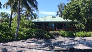 A beachfront property with a clear pool, a wooden deck, and a house with a green roof. - Private beach front property, the perfect getaway! Enjoy our slice of paradise. (Waimea)