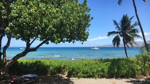 A wooden deck overlooking a beach with a view of the ocean and a sailboat. - Private beach front property, the perfect getaway! Enjoy our slice of paradise. (Waimea)