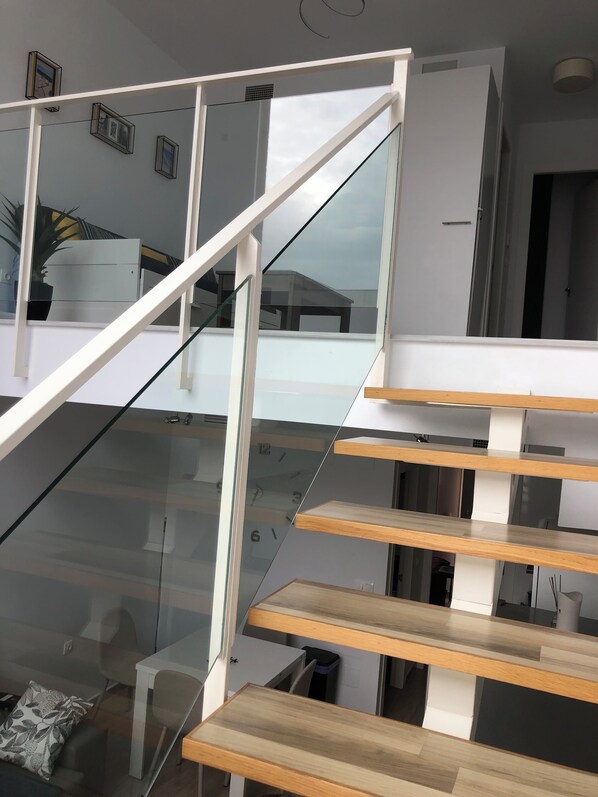 Eine moderne Treppe mit Glasgeländern und Holzboden, die zu einer oberen Etage führt.