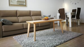 Una sala moderna con un sofá, una mesa de centro de madera, una mesa de comedor con sillas y un reloj de pared.