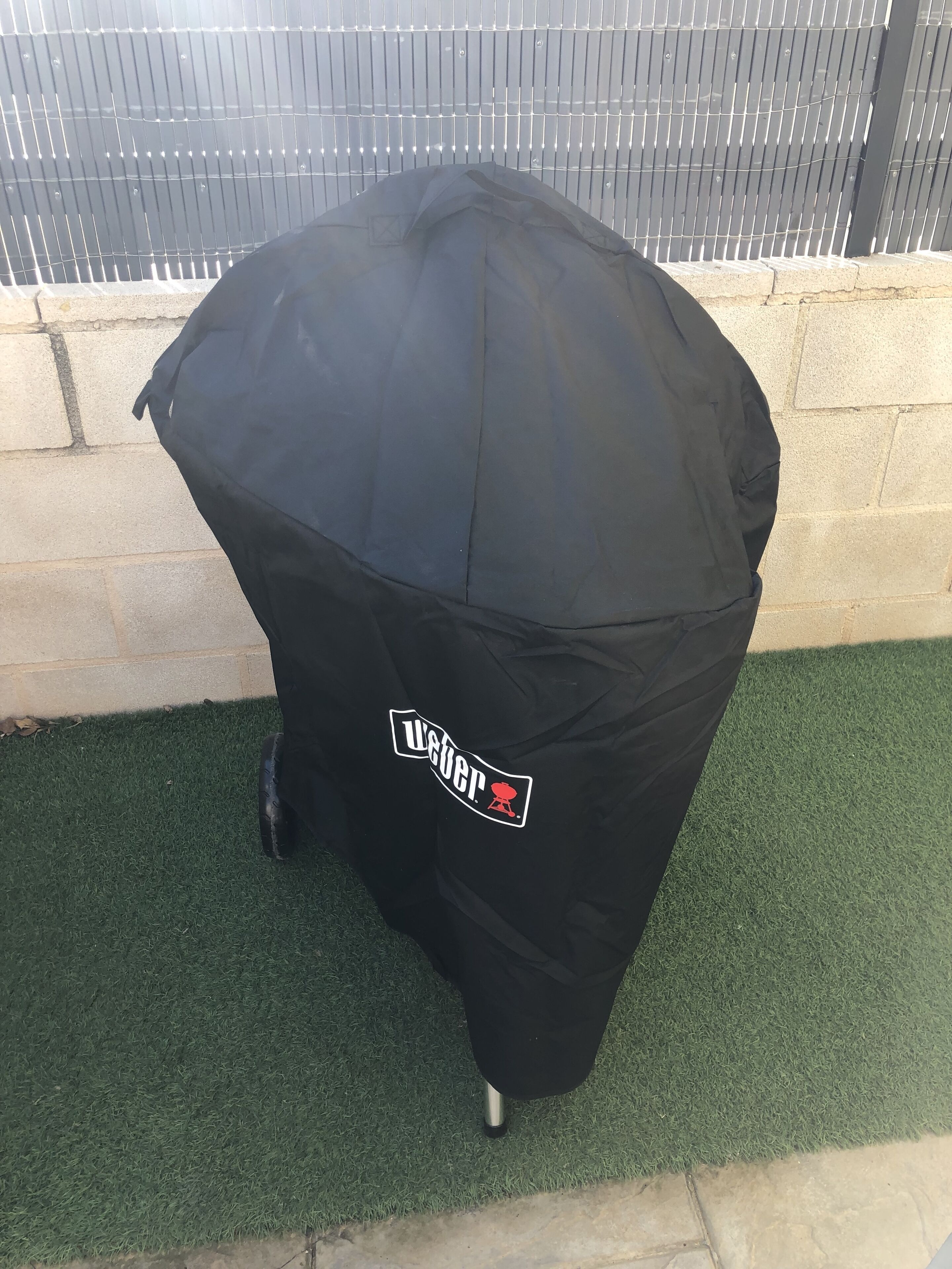 A black umbrella with a logo on it, placed on artificial grass.