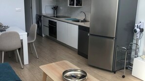 Una cocina moderna con un refrigerador de acero inoxidable, un lavamanos y un comedor con mesa y sillas.