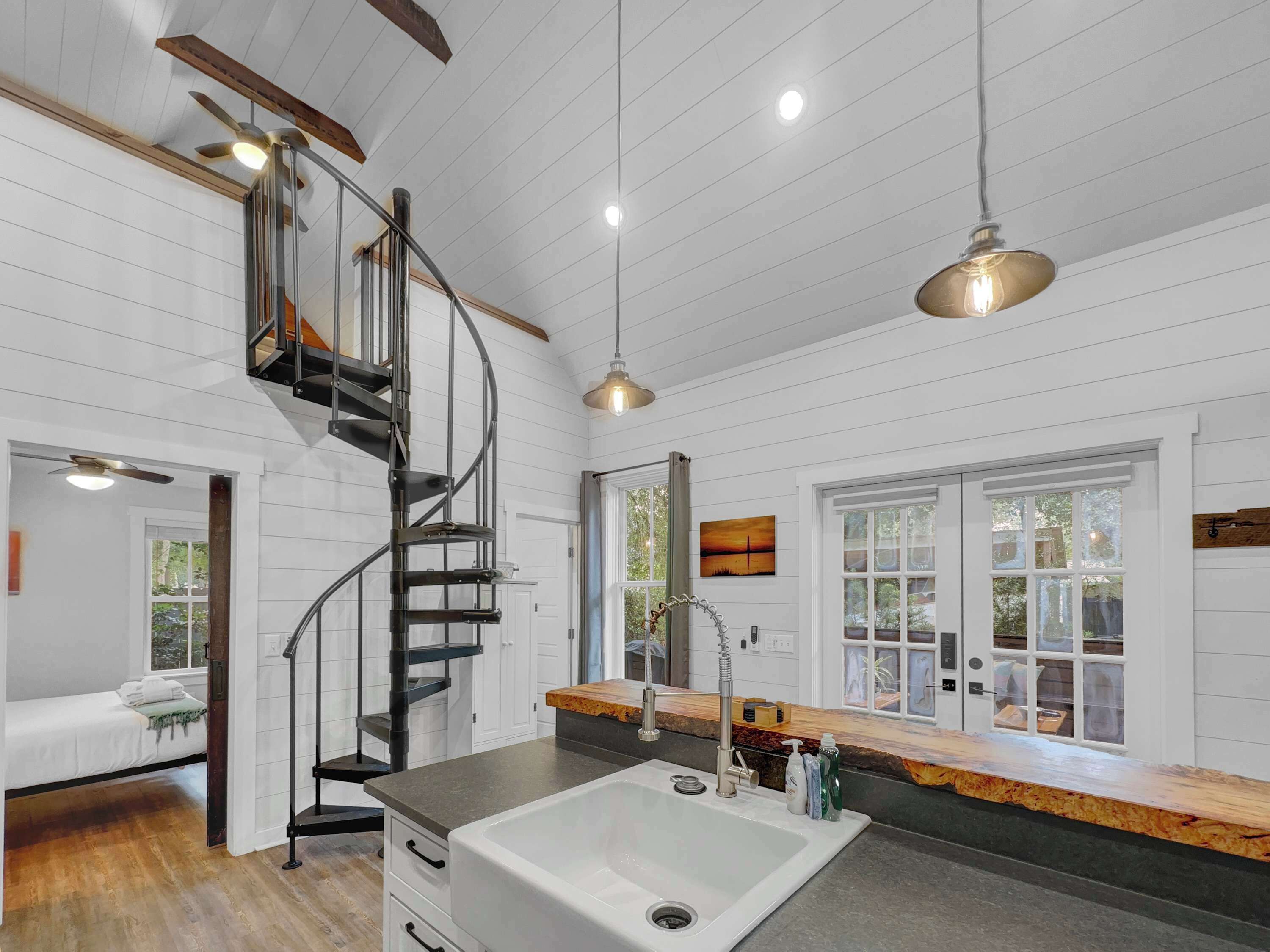 A modern kitchen with a built-in stove, a large island with a sink, and a spiral staircase.