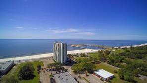 A high-rise hotel with a parking lot and a beach view.
