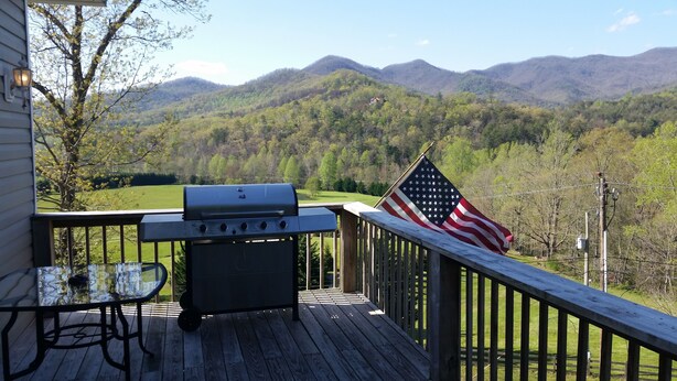 Una terraza con una parrilla y una bandera estadounidense, con vistas a un paisaje montañoso.