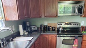 Una cocina con armarios de madera, electrodomésticos de acero inoxidable, un lavamanos y una encimera.