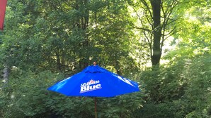 A wooden bench under a blue umbrella with the text "Levititt Blue" in a garden setting. - StarField Cottage...The Perfect Cooperstown Dreams Park Getaway! (Cooperstown)