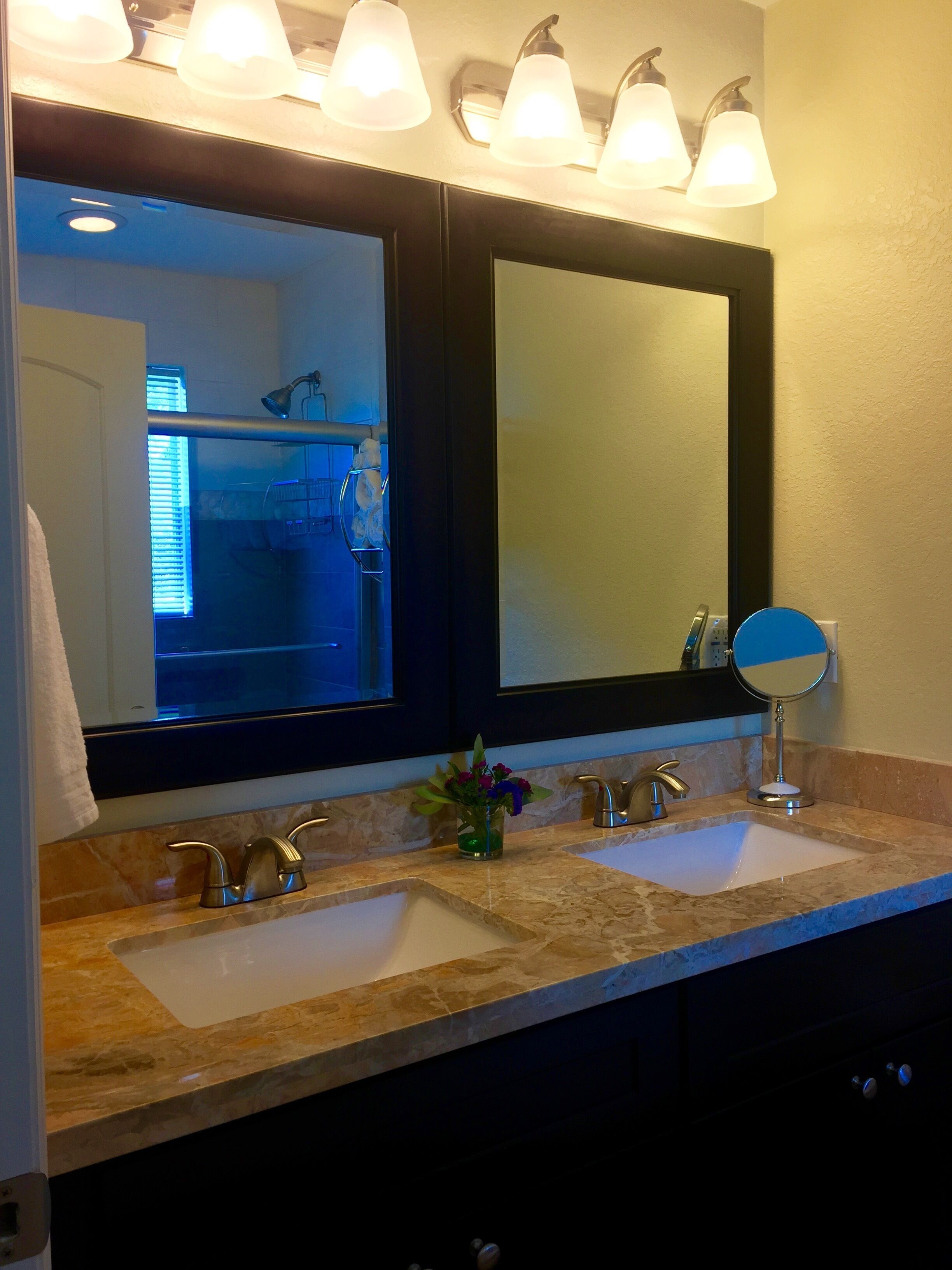 A bathroom with two sinks, a mirror, and a towel rack.