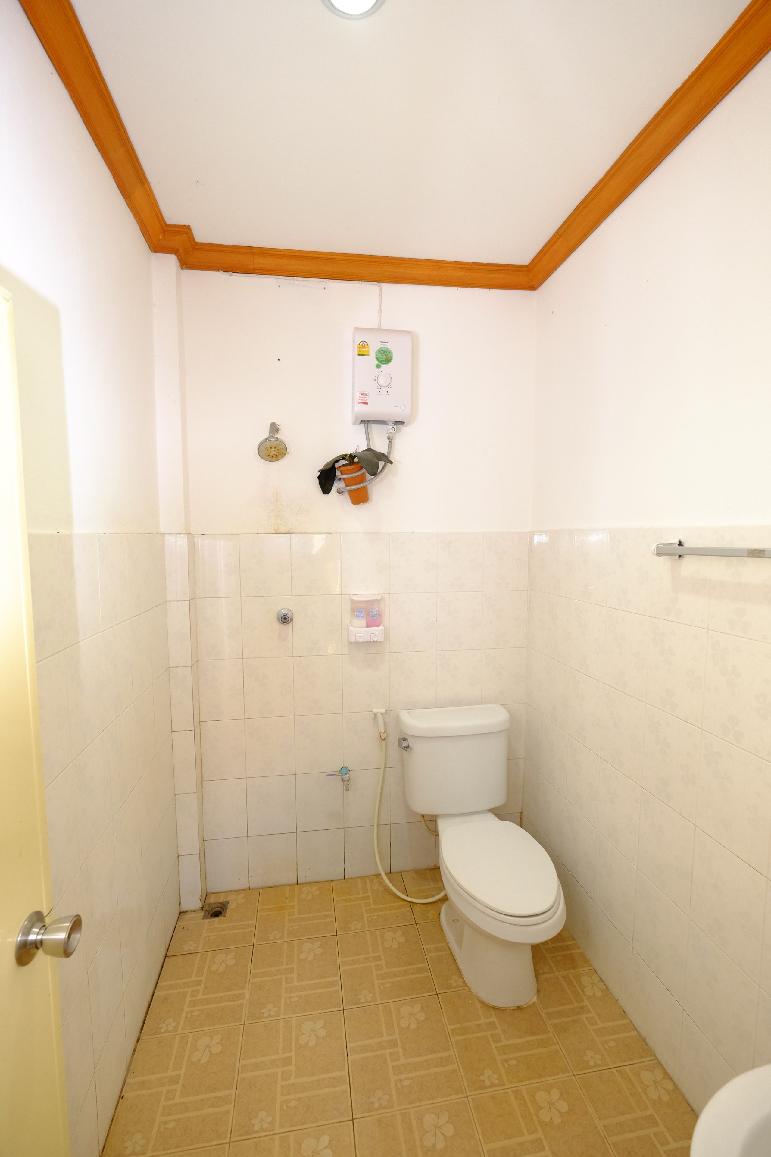 Un baño pequeño y funcional con inodoro, ducha y calentador de agua instalado en la pared.