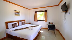 Habitación de hotel con una cama grande, un escritorio con silla, un televisor montado en la pared y una ventana con cortinas.
