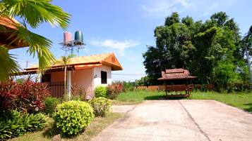 A residential property with a paved driveway, a small house with a tiled roof, and a water tank on a metal structure.