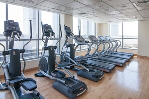 Ein Fitnessraum mit Laufbändern, Crosstrainern und Ergometer, die in Reihen angeordnet sind.