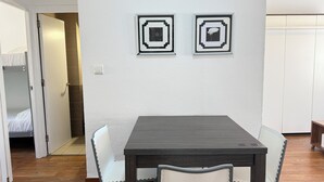 A dining area with a dark wooden table and white chairs, two framed pictures on the wall, and a door leading to a bedroom. - Agi Josep Sabate 42 Apartamento for rent in Roses Girona. (Rosas / Roses)