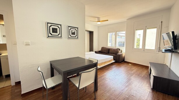 A modern living room with a dining table, two chairs, a sofa, and a TV. - Agi Josep Sabate 42 Apartamento for rent in Roses Girona. (Rosas / Roses)
