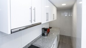 Een moderne keuken met witte kastjes, een koffiezetapparaat en een aanrecht.